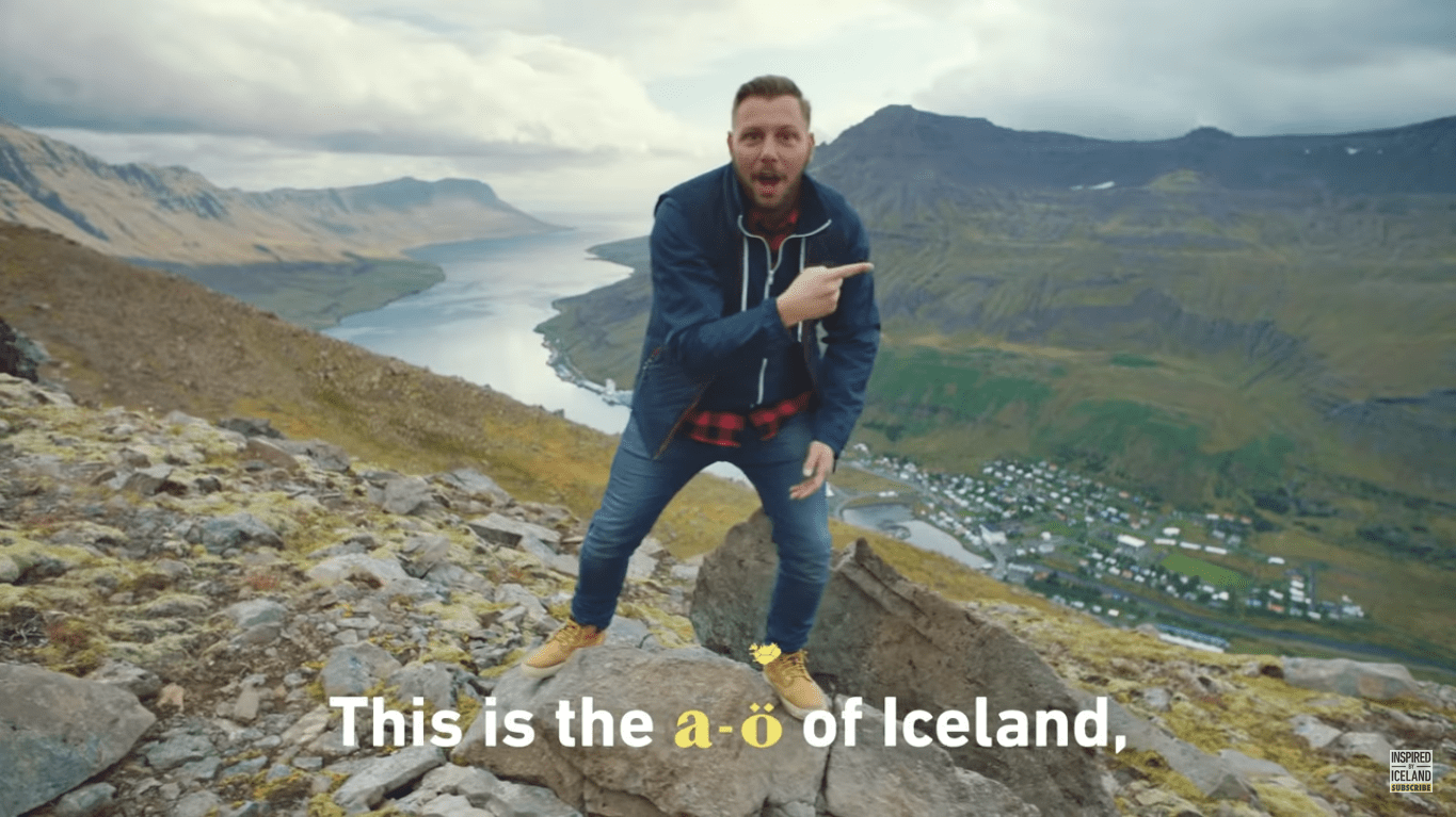 Picture of man on a mountain singing “The A to Ö of Iceland.”